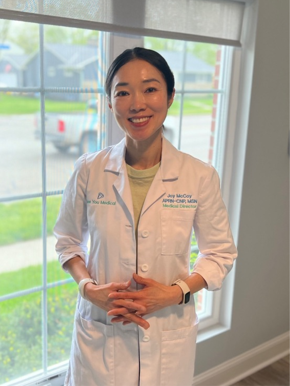 Joy McCoy, APRN-CNP, MSN, Medical Director, wearing white medical coat at clinic window