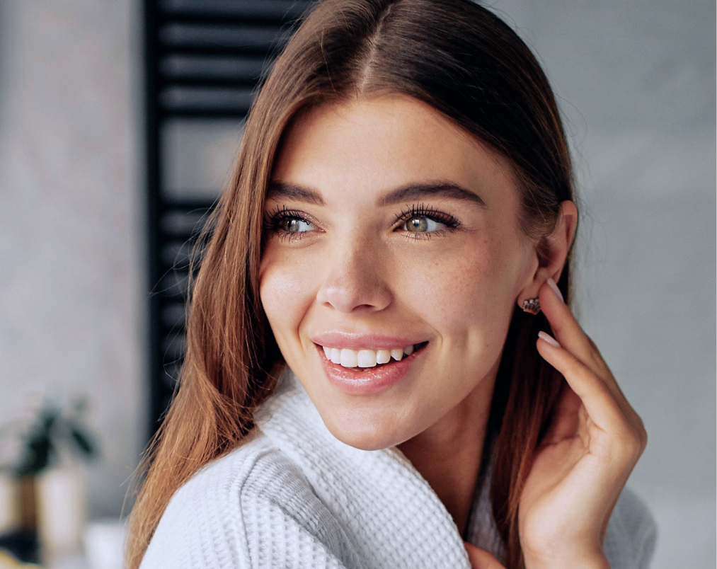 Woman with long brown hair smiling at camera in modern interior setting