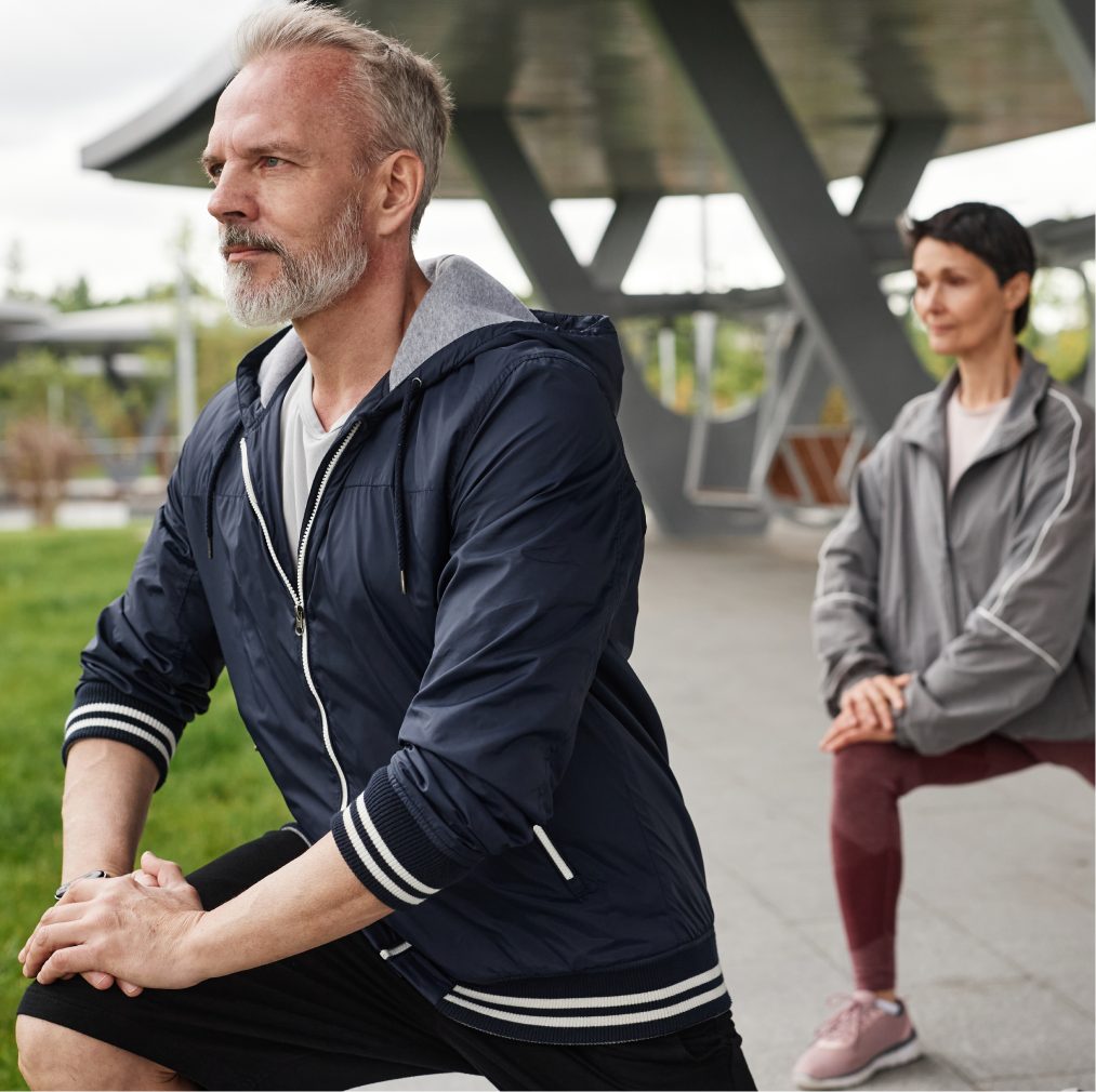 Middle-aged man and woman stretching before exercising outdoors