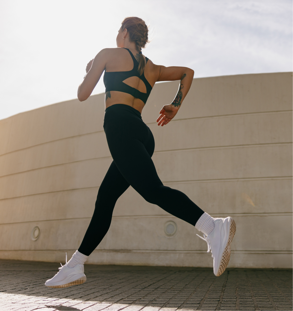Woman jogging outdoors in black sports attire and white shoes