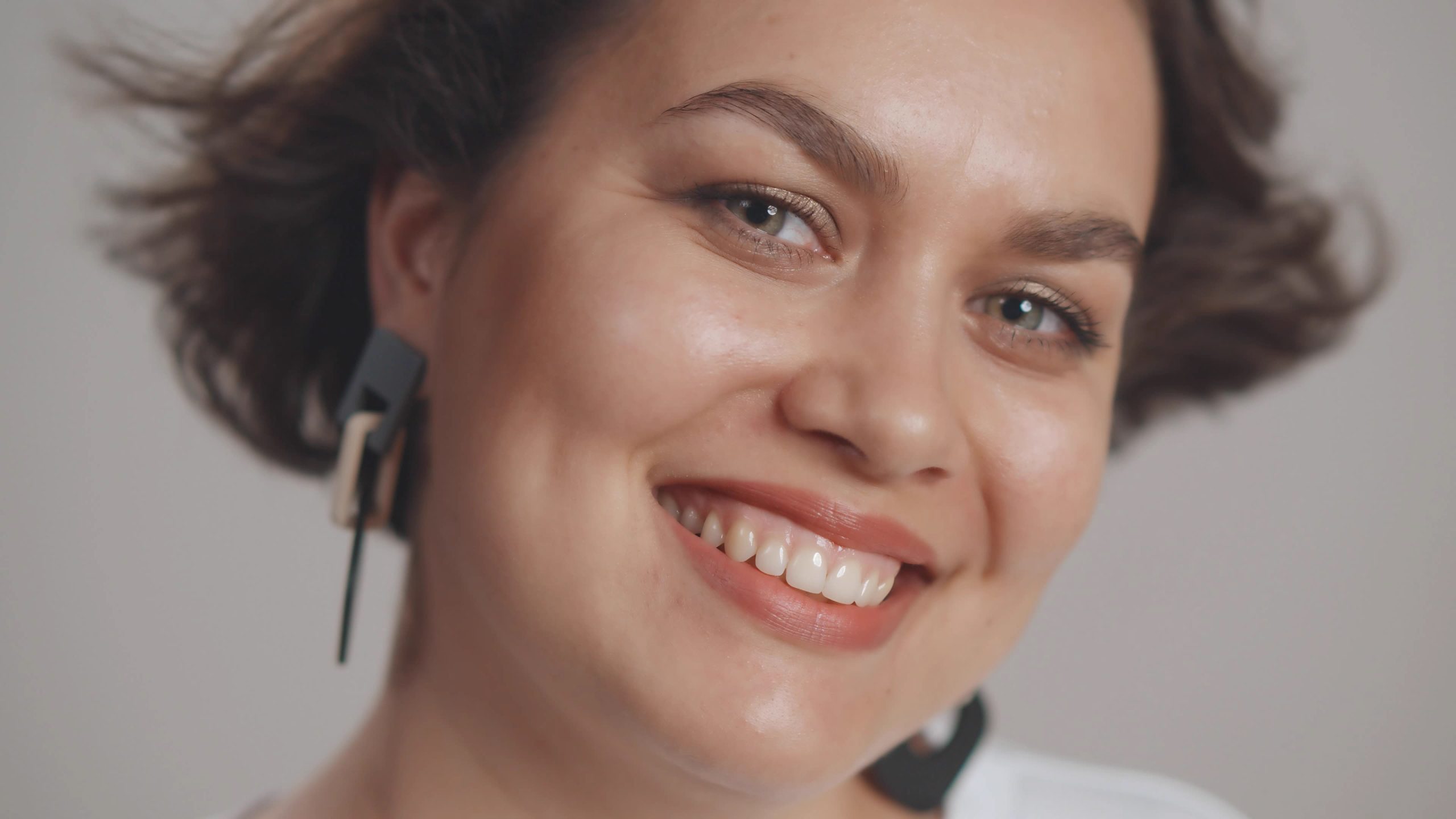 Woman smiling at camera with earbuds in