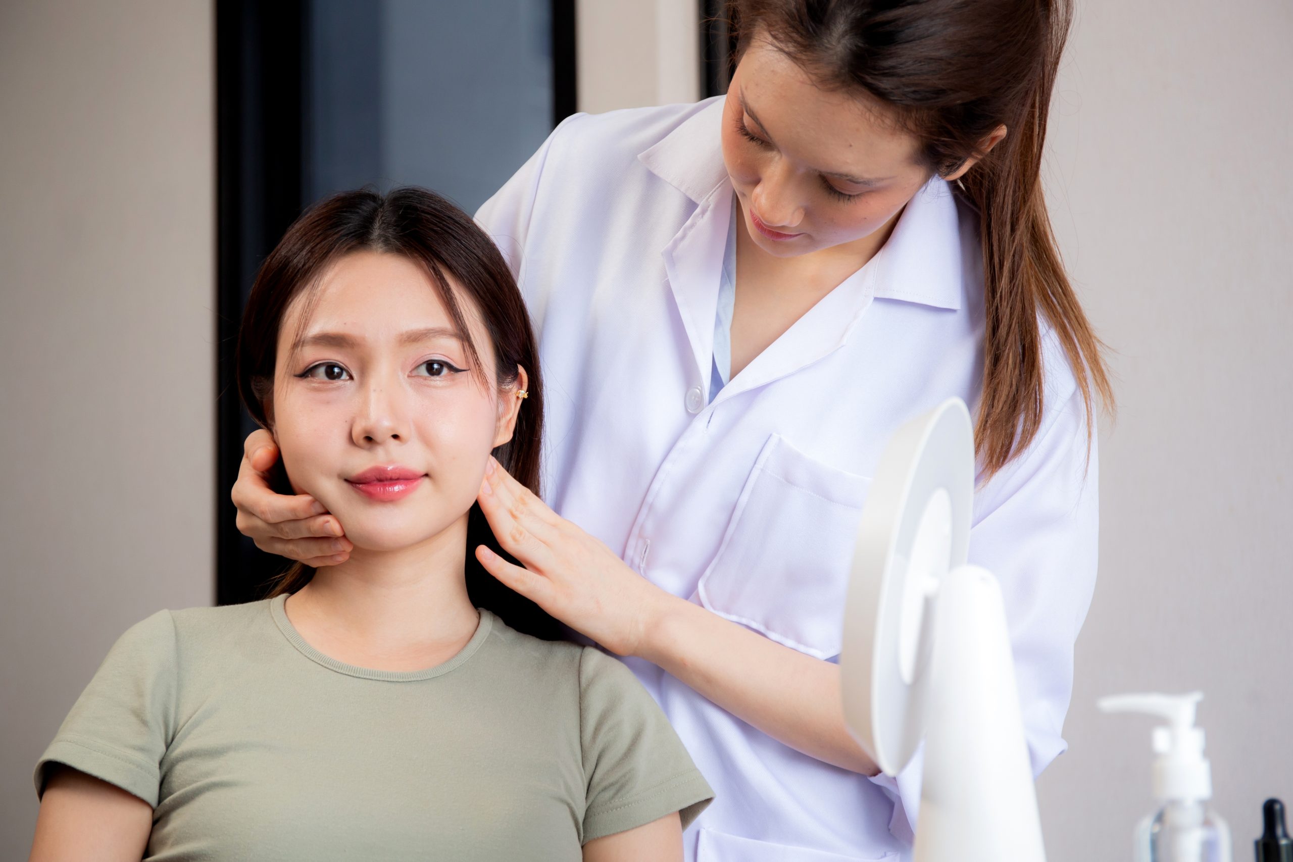 Doctor in white coat examining patient's neck and jaw during consultation