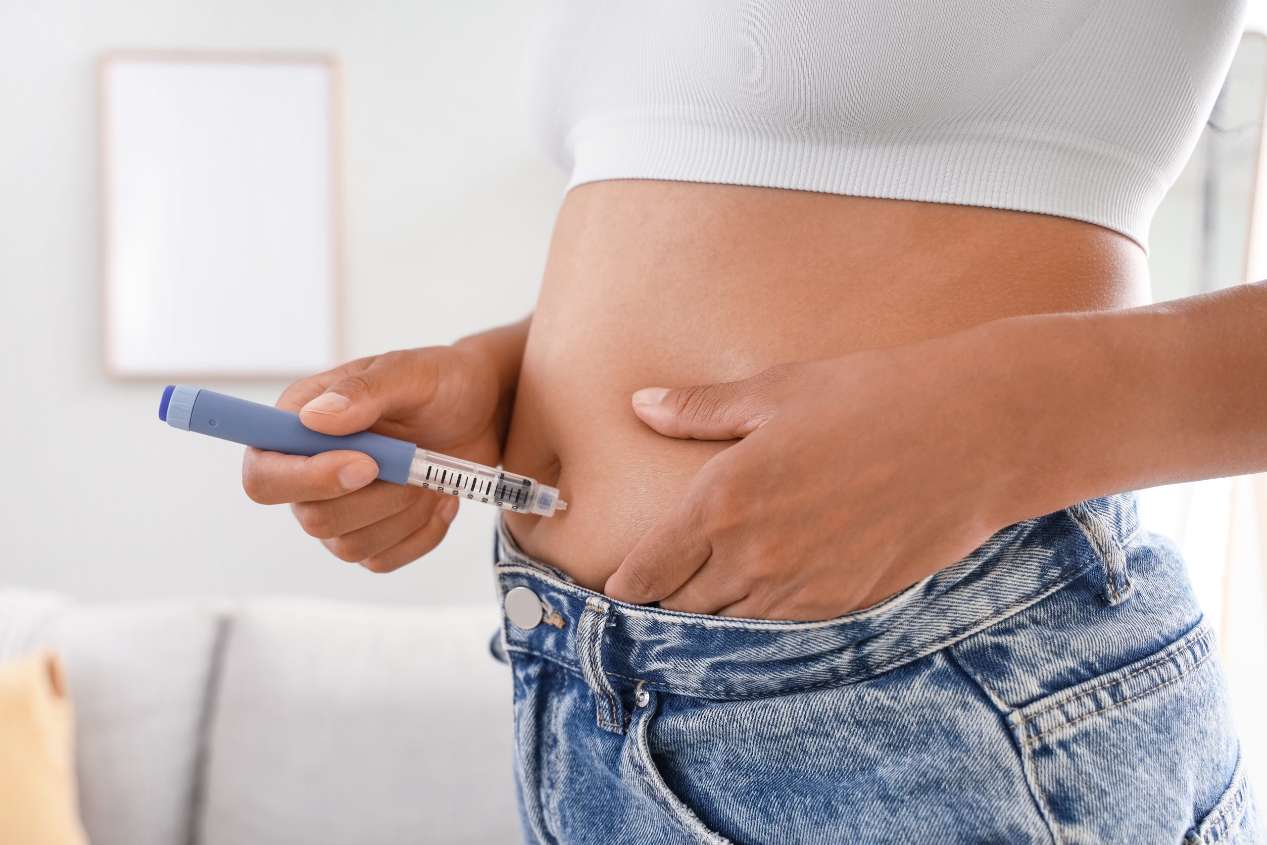 Woman self-administering injection into abdomen at home