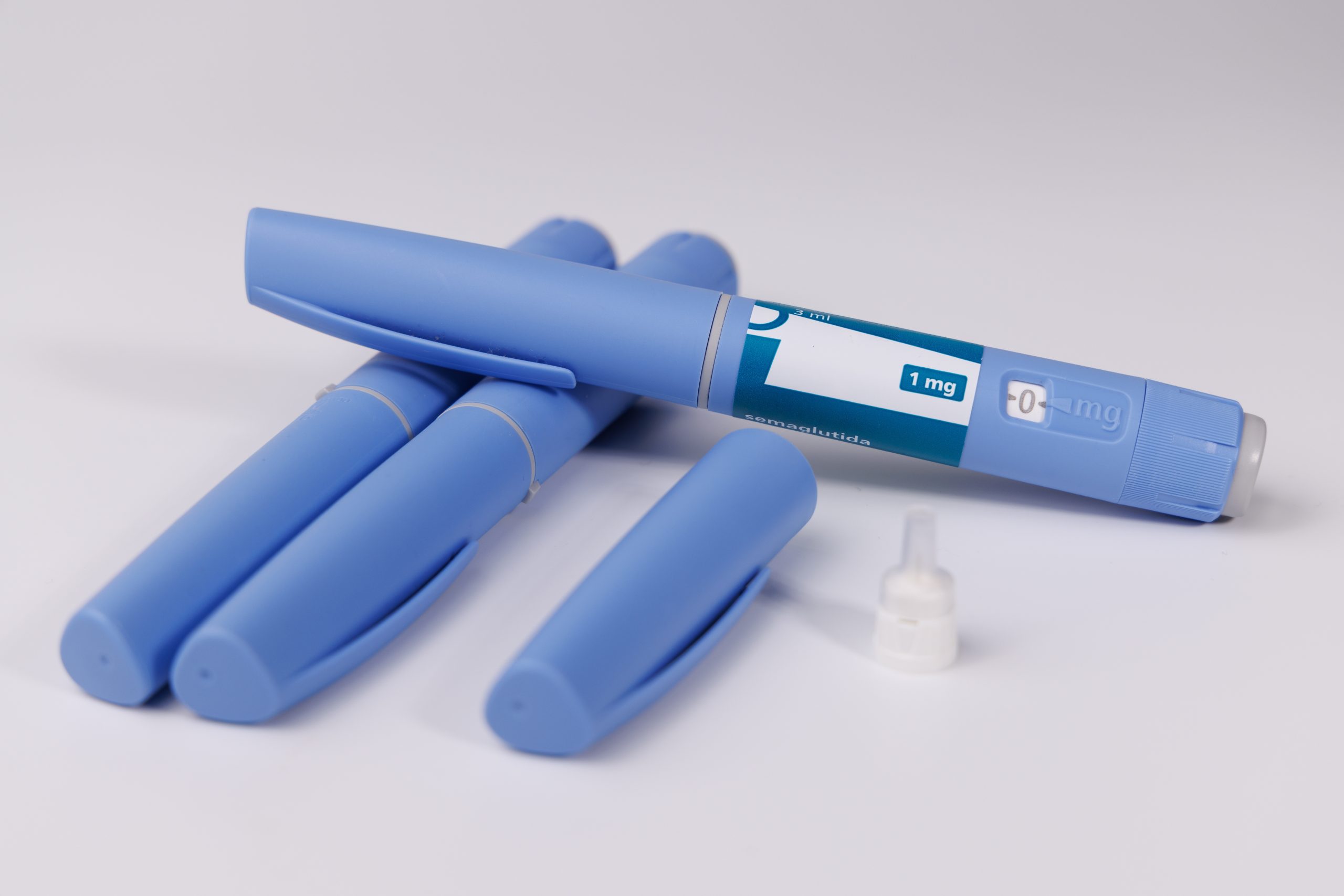 Blue pre-filled injection pens and vials on white surface
