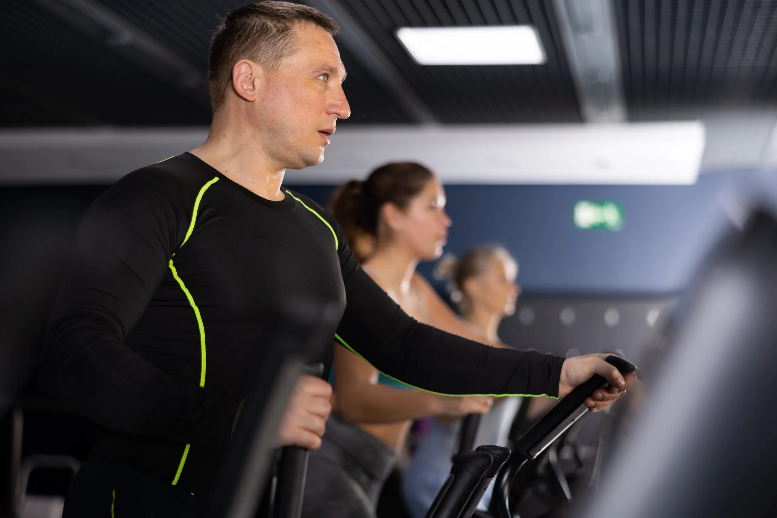 Man training on an elliptical machine at the gym to break through an athletic plateau