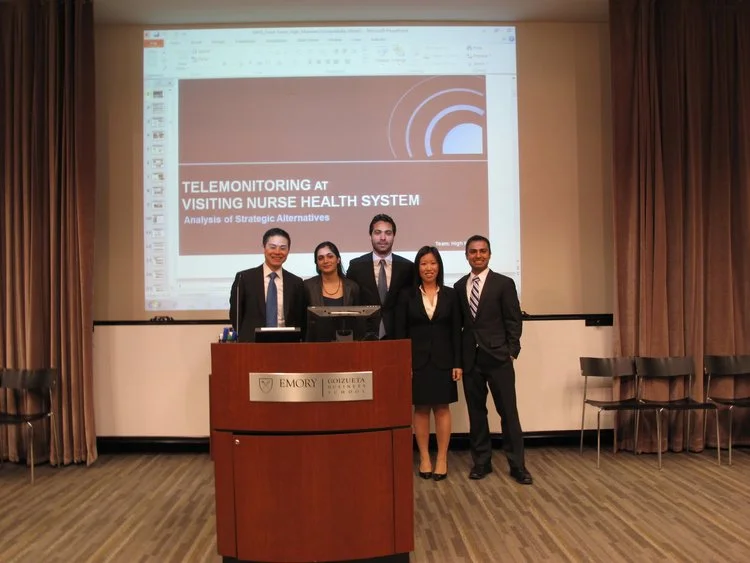 Five professionals presenting at an Emory podium with a slide about telemonitoring at visiting nurse health system