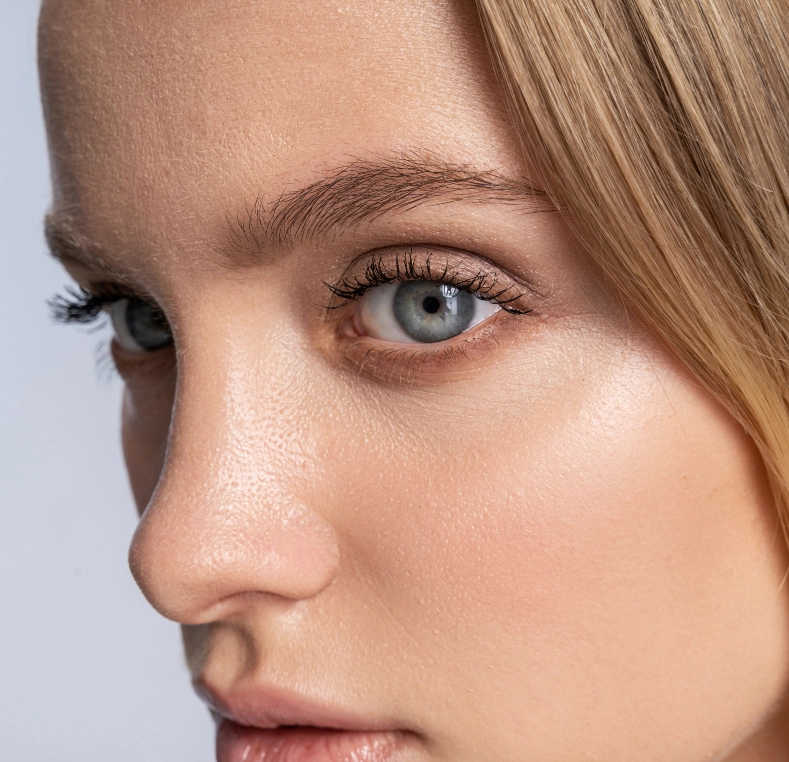 Woman's face in profile showing eye, eyebrow, nose, and lips against neutral background