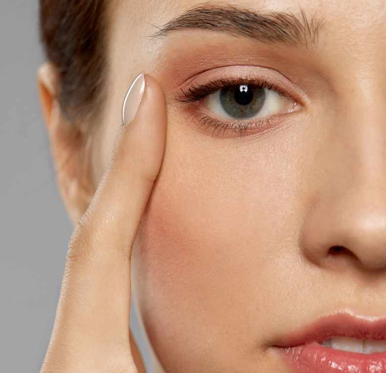 Woman holding contact lens on fingertip near her eye
