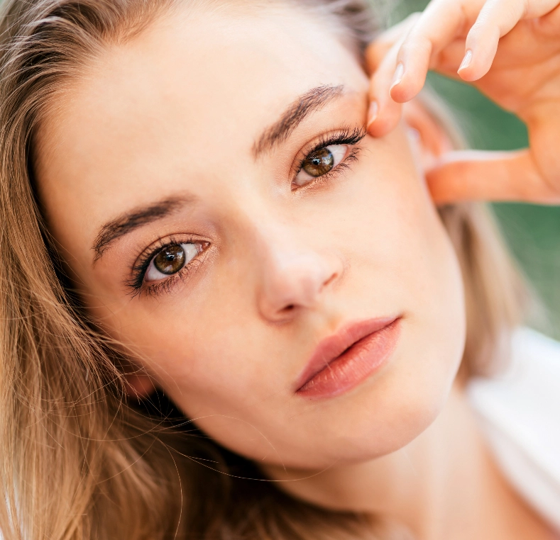 Woman touching area near her eye while looking to the side