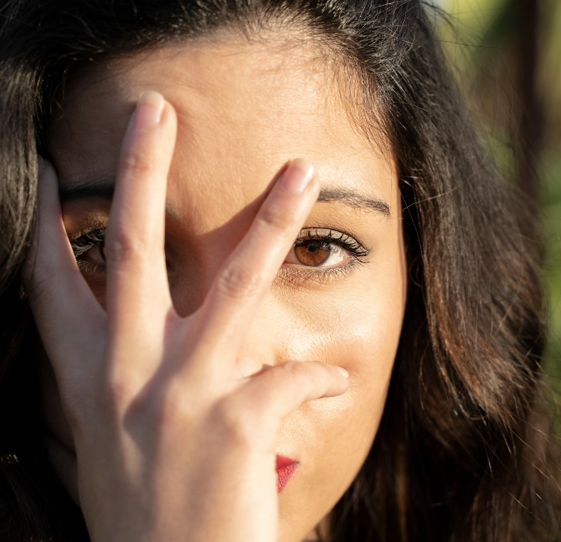Woman shielding her eye with hand while looking away outdoors