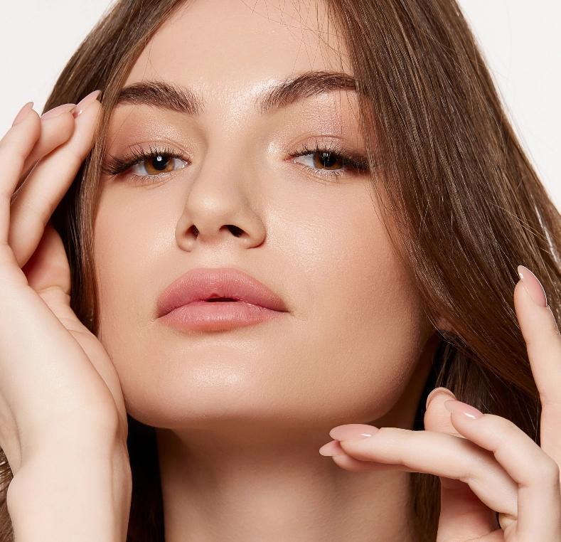 Woman touching her face with hands, displaying clear skin and defined facial features