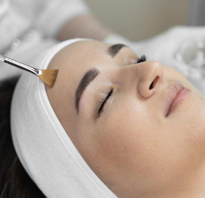 Esthetician brushing chemical peel solution onto patient's face