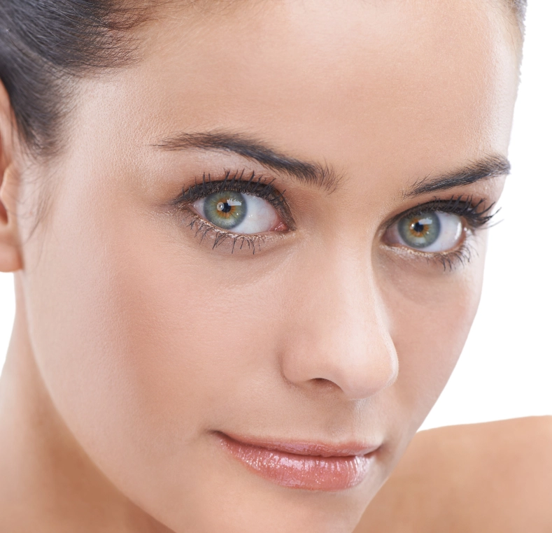 Woman with blue-hazel eyes and defined eyebrows looking at camera with slight smile