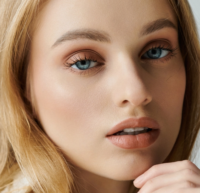 Woman with blue eyes and reddish eyeshadow looking to the side
