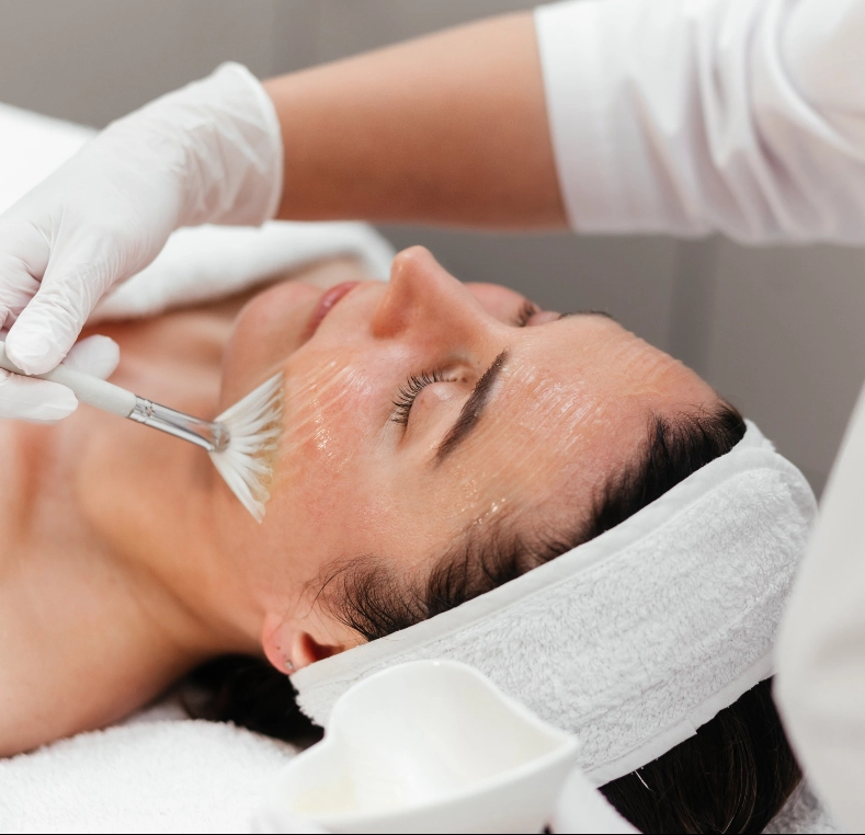 Aesthetician applying facial treatment with brush to patient's face