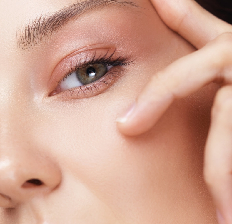Close-up of woman's eye with hand near eyelid showing eyeliner and eyebrow