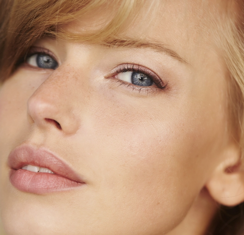 Woman's face in profile with blue-gray eyes and blonde hair with bangs