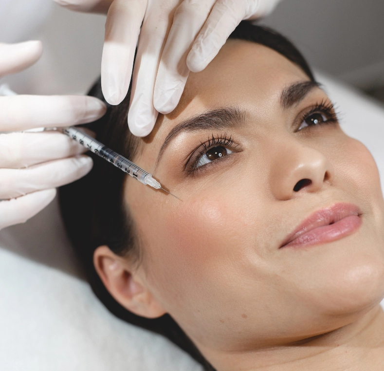 Practitioner injecting filler near patient's eyebrow area with syringe