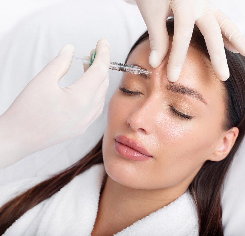 Practitioner injecting filler into forehead area of patient lying down