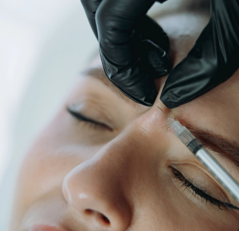 Practitioner applying permanent makeup or microblading to patient's eyebrow