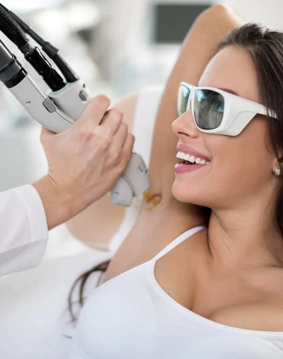 Practitioner using laser hair removal device on patient's underarm while patient wears protective eyewear