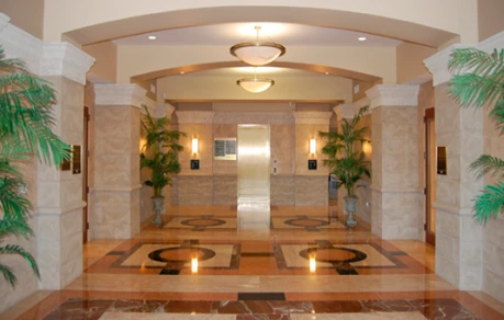 Elegant medical office lobby with marble columns, potted plants, recessed lighting, and polished flooring