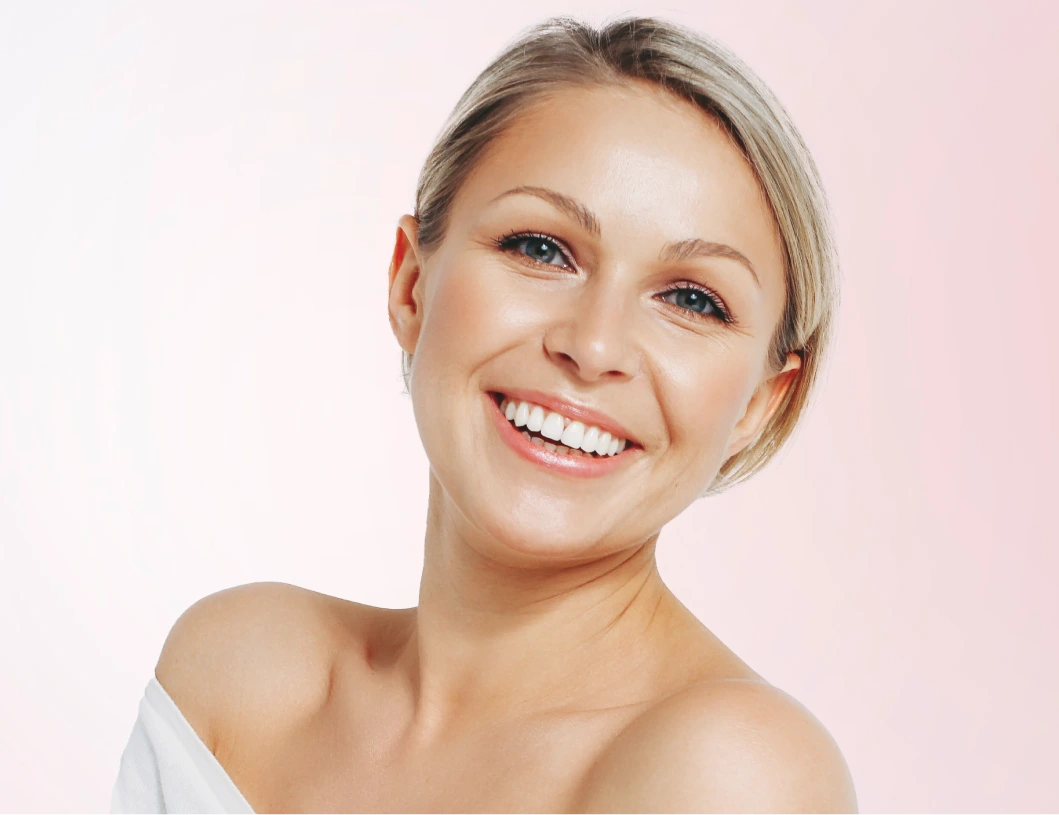 Woman with radiant skin and bright smile against soft pink background