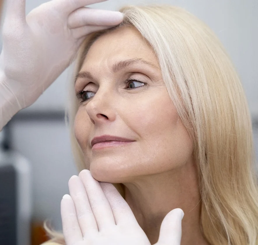 Surgeon examining a mature patient's face during a facelift consultation