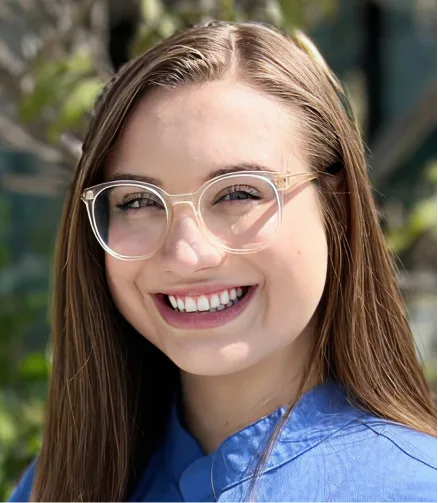 Woman wearing clear-frame glasses and blue shirt smiling outdoors