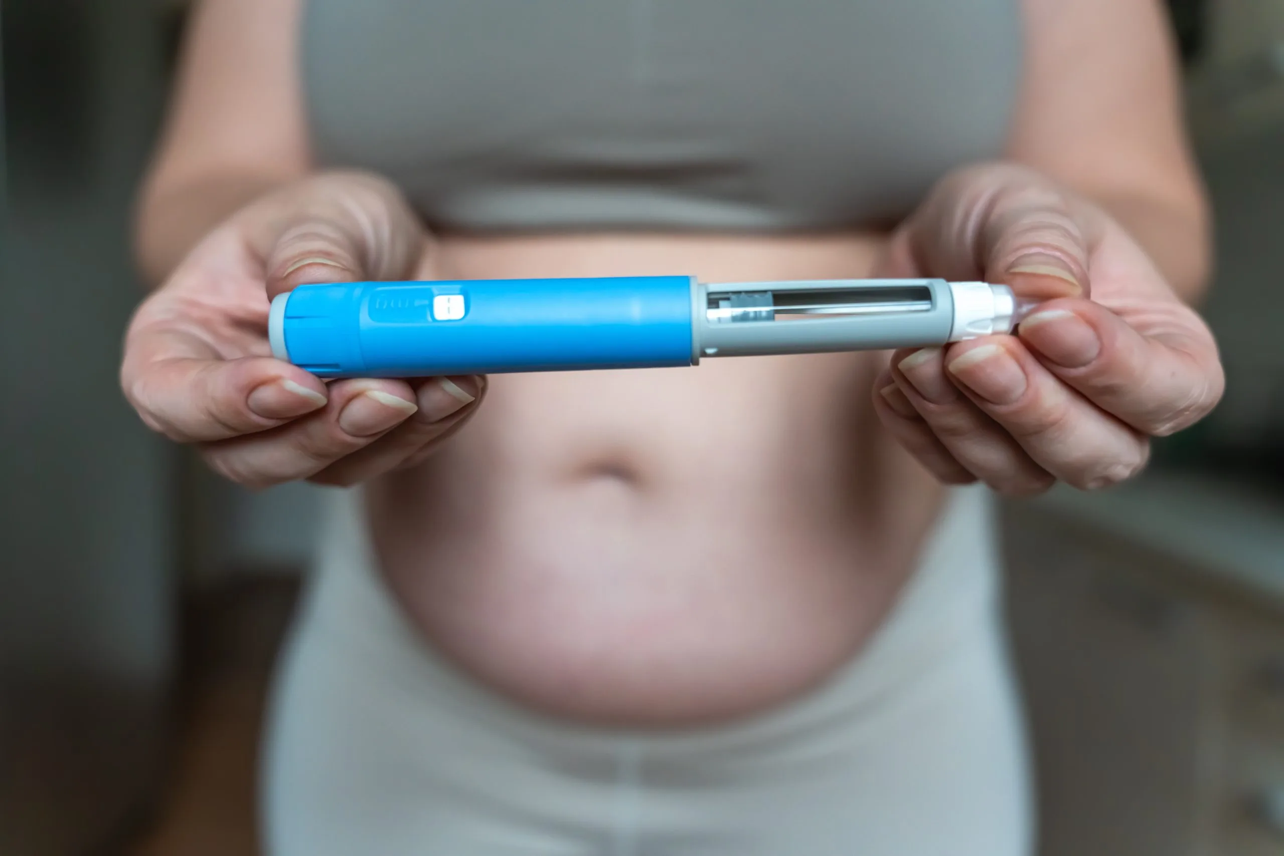 Woman holding a blue GLP-1 injection pen for weight loss treatment