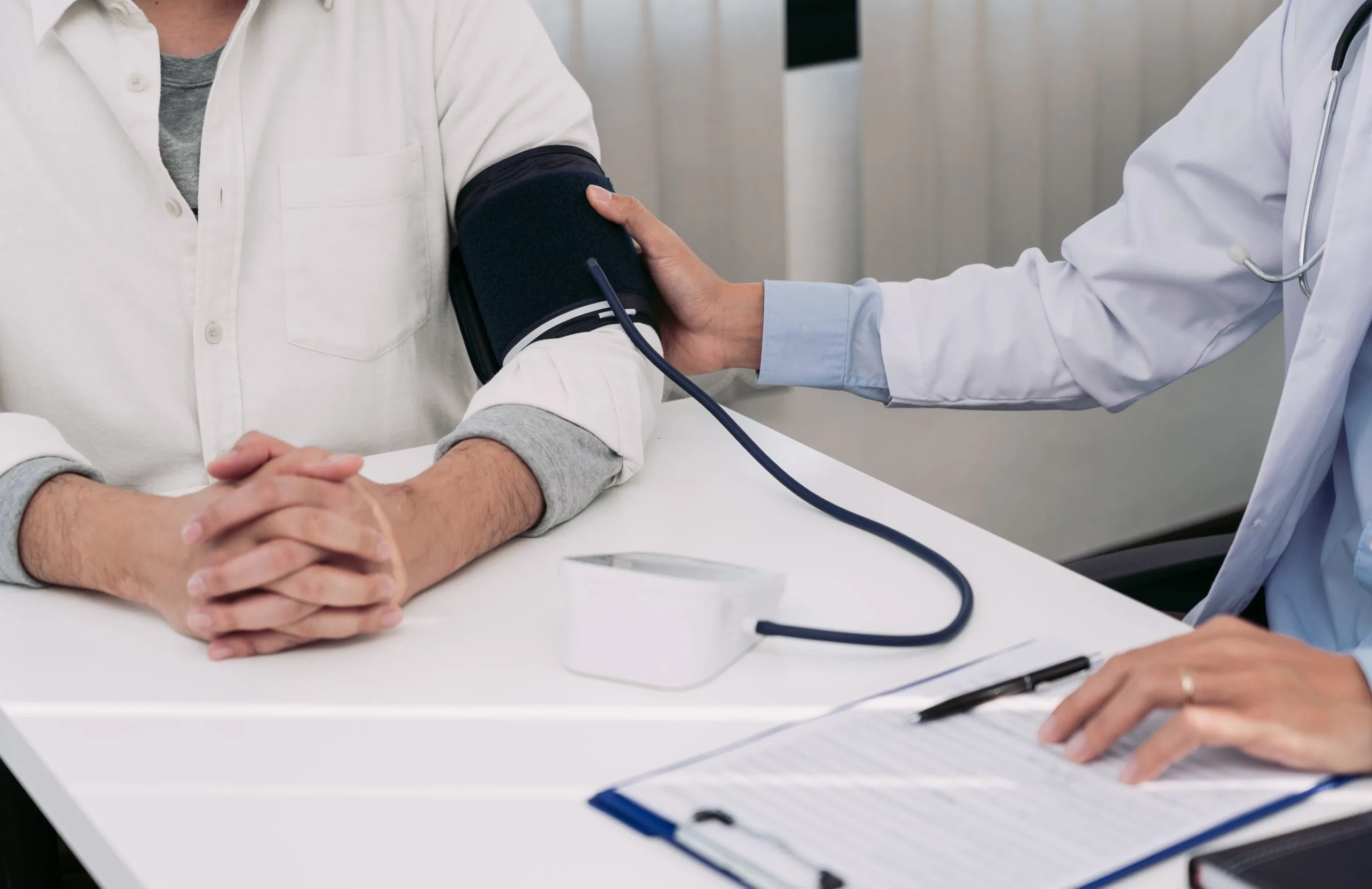 Doctor taking blood pressure reading on patient's arm using manual cuff
