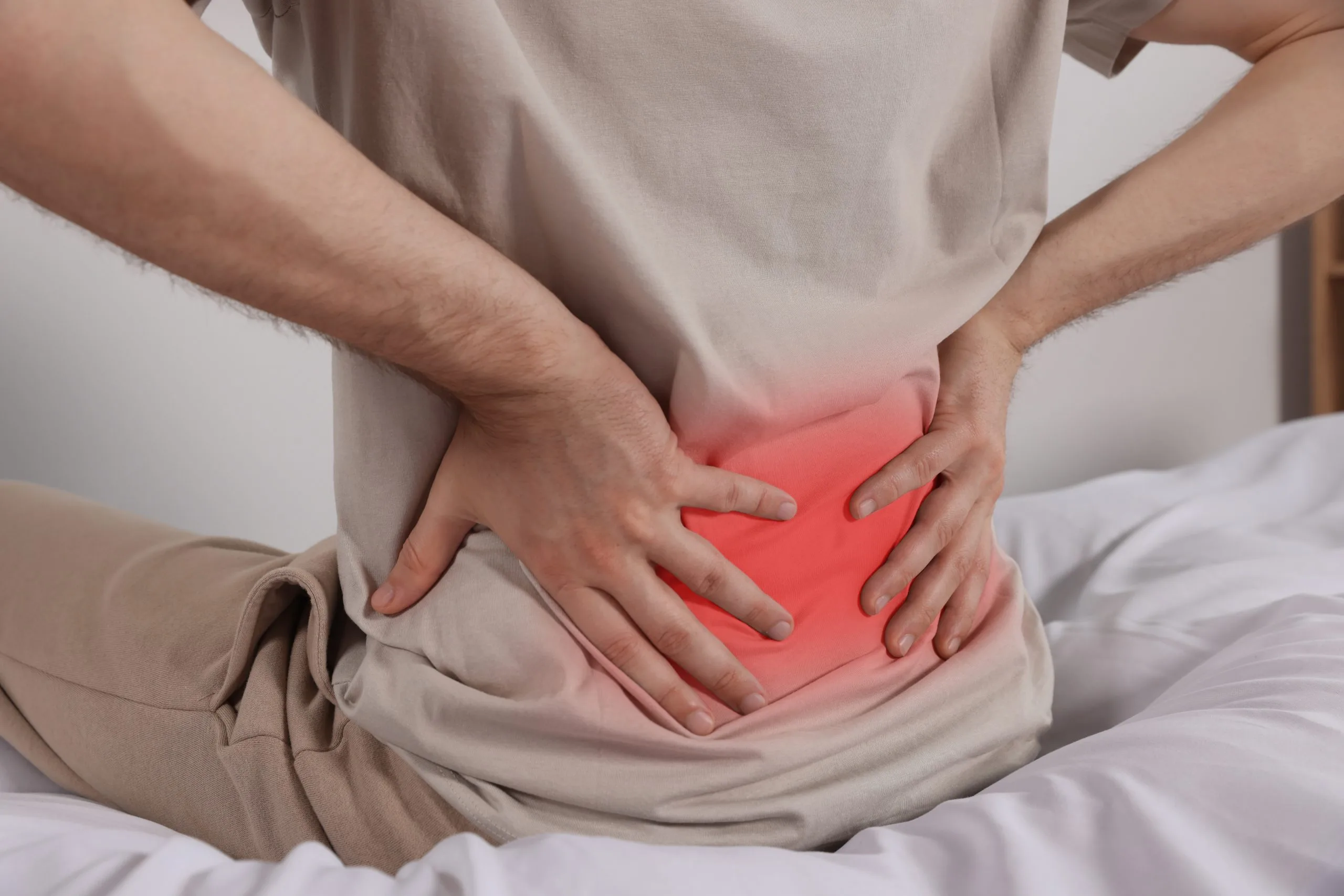 Man holding lower back with both hands, highlighting lower back pain in red