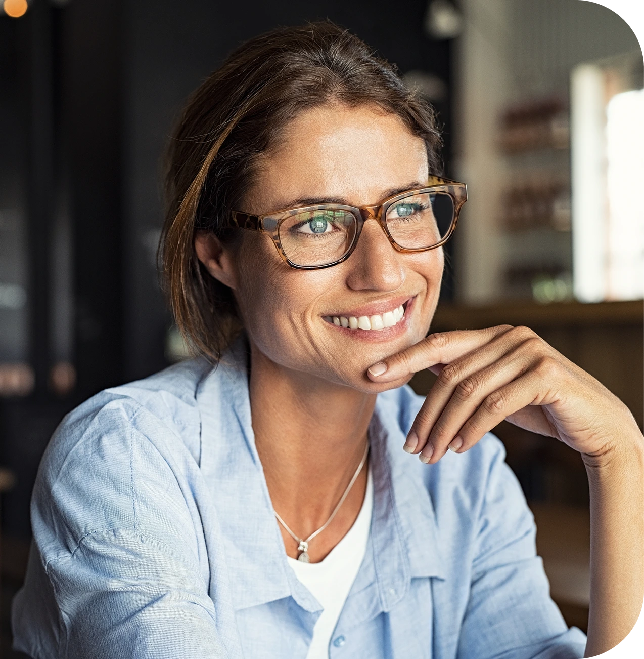 Smiling woman wearing glasses and light blue shirt in indoor setting
