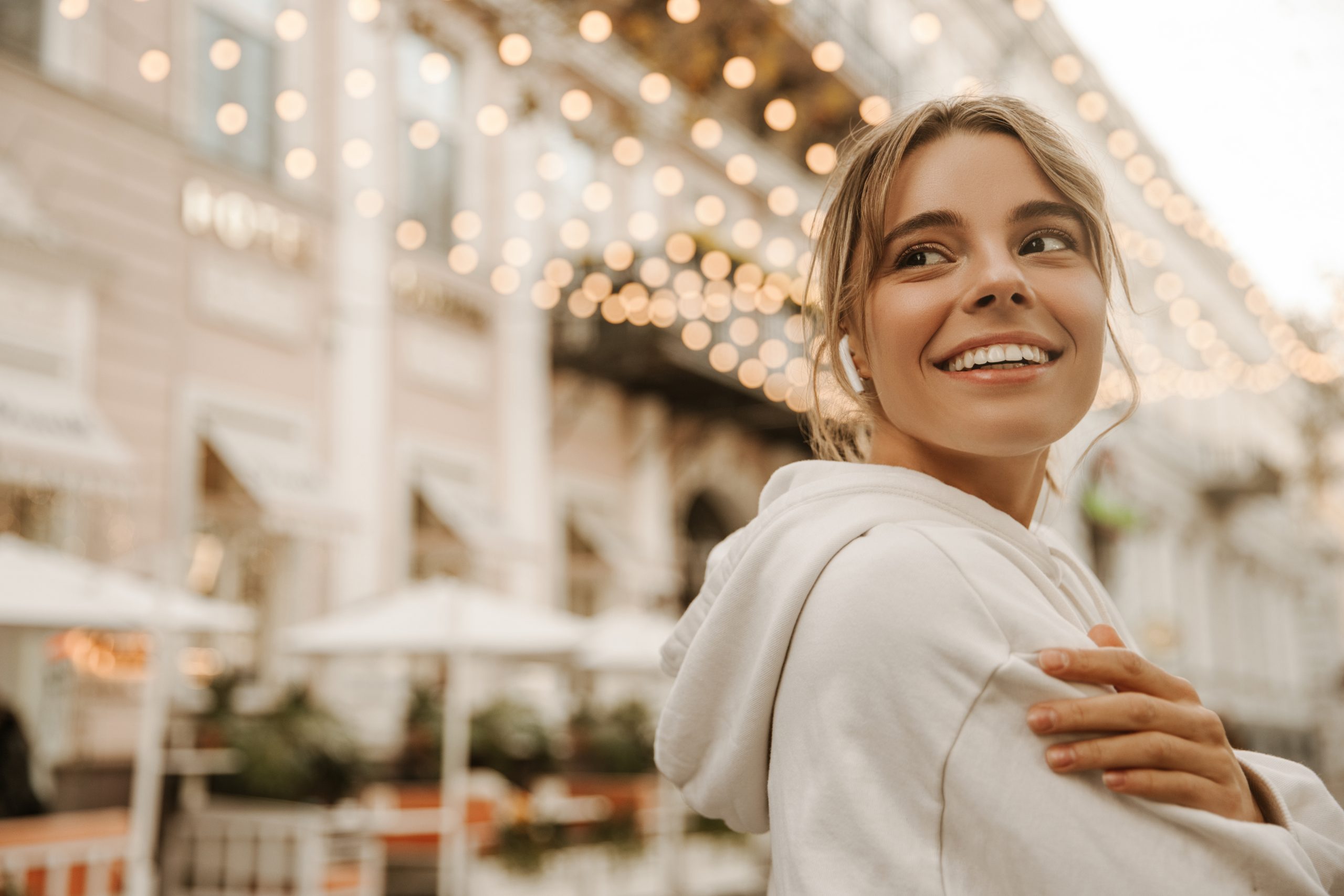 Woman smiling outdoors under string lights