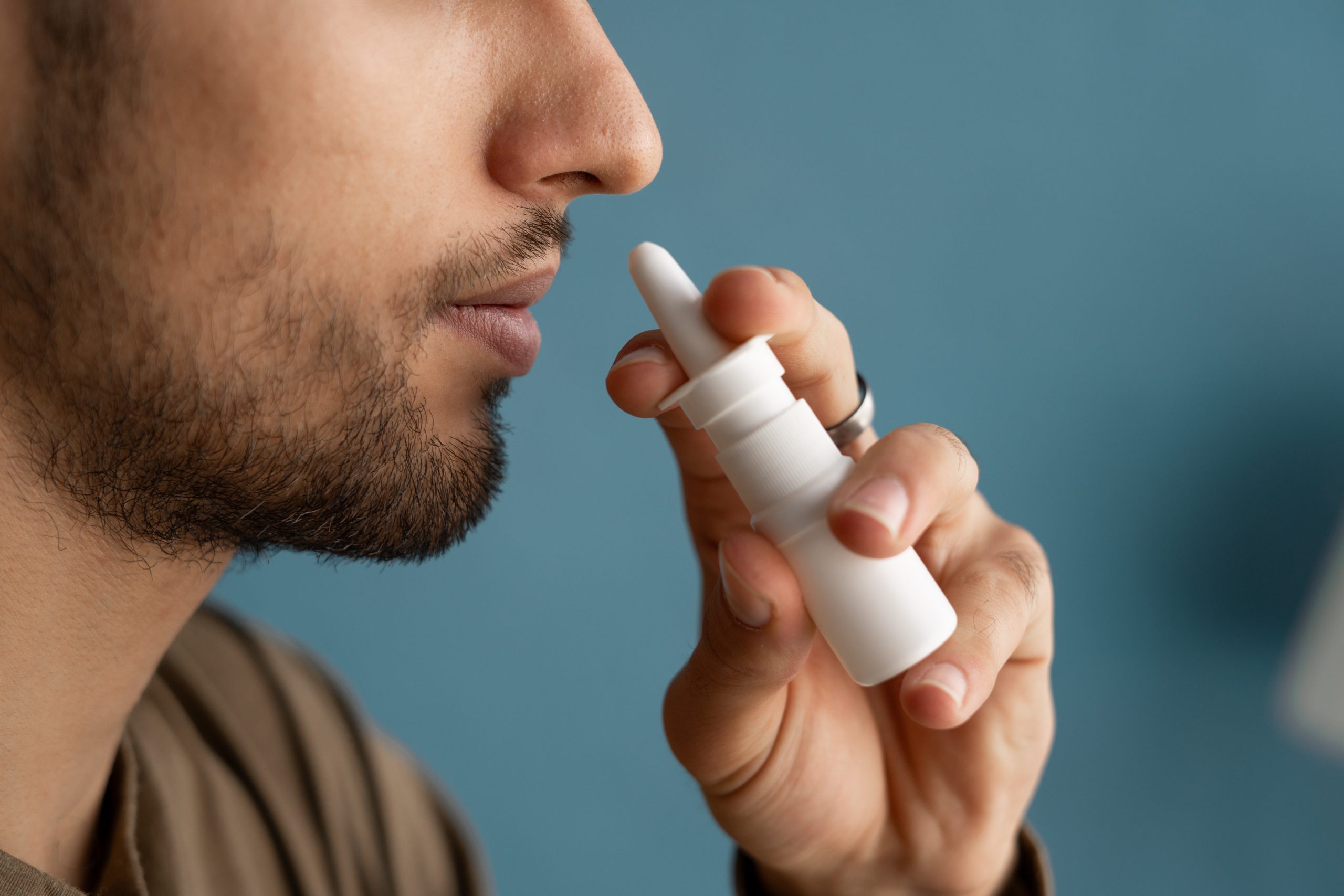Man applying nasal spray to his nose