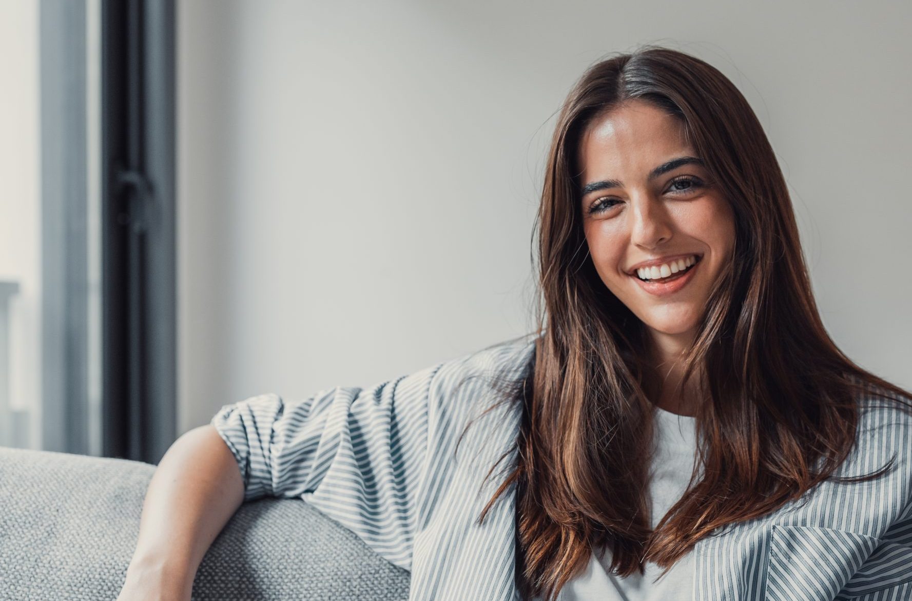 Woman smiling on couch in bright natural light