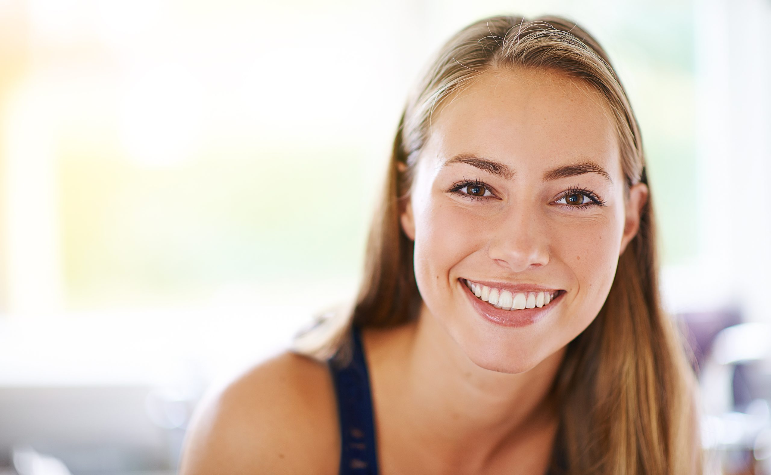 Woman with long reddish-brown hair smiling brightly in bright clinic environment