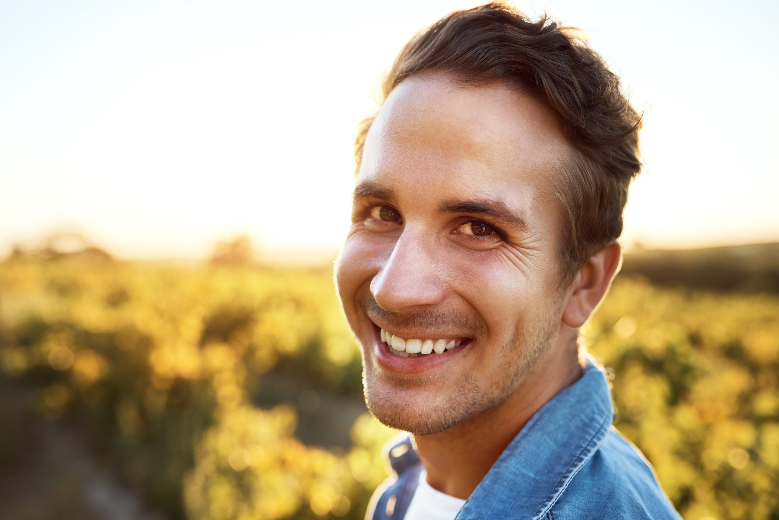 Man smiling in sunflower field at golden hour