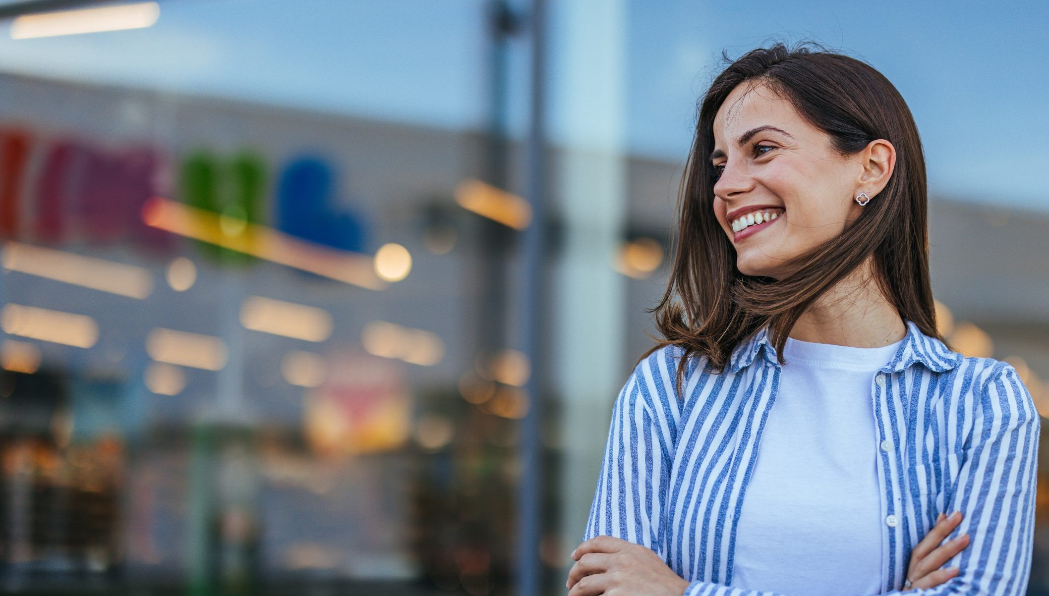 Woman in striped shirt smiling with arms crossed