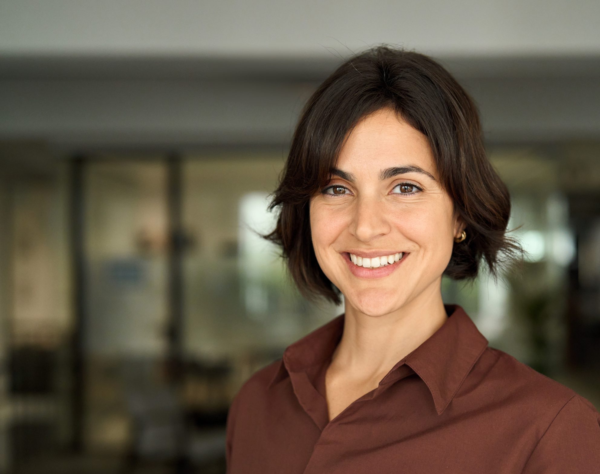 Woman with dark hair smiling at camera in modern clinic interior