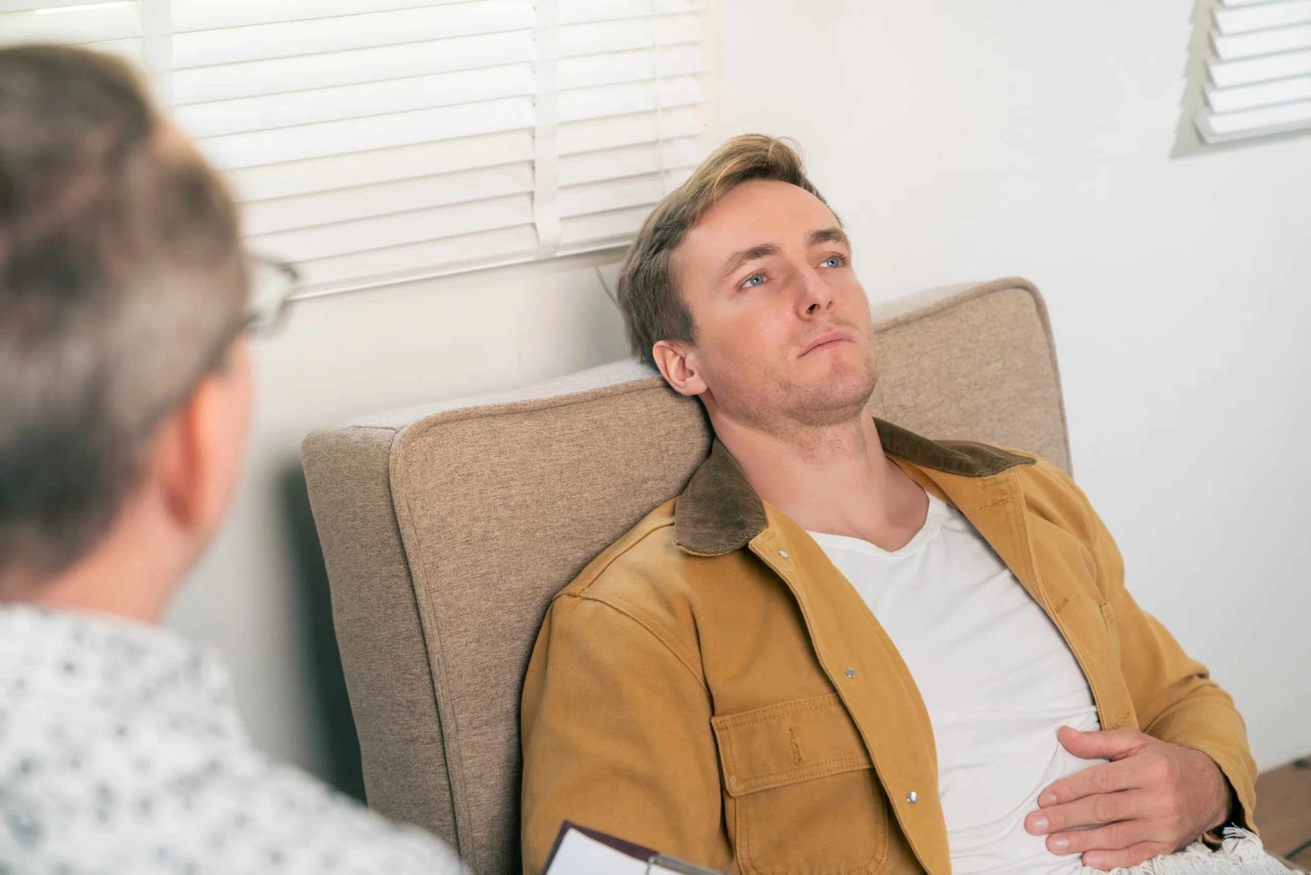 Psychiatrist listening to male patient discuss mental health concerns during a consultation