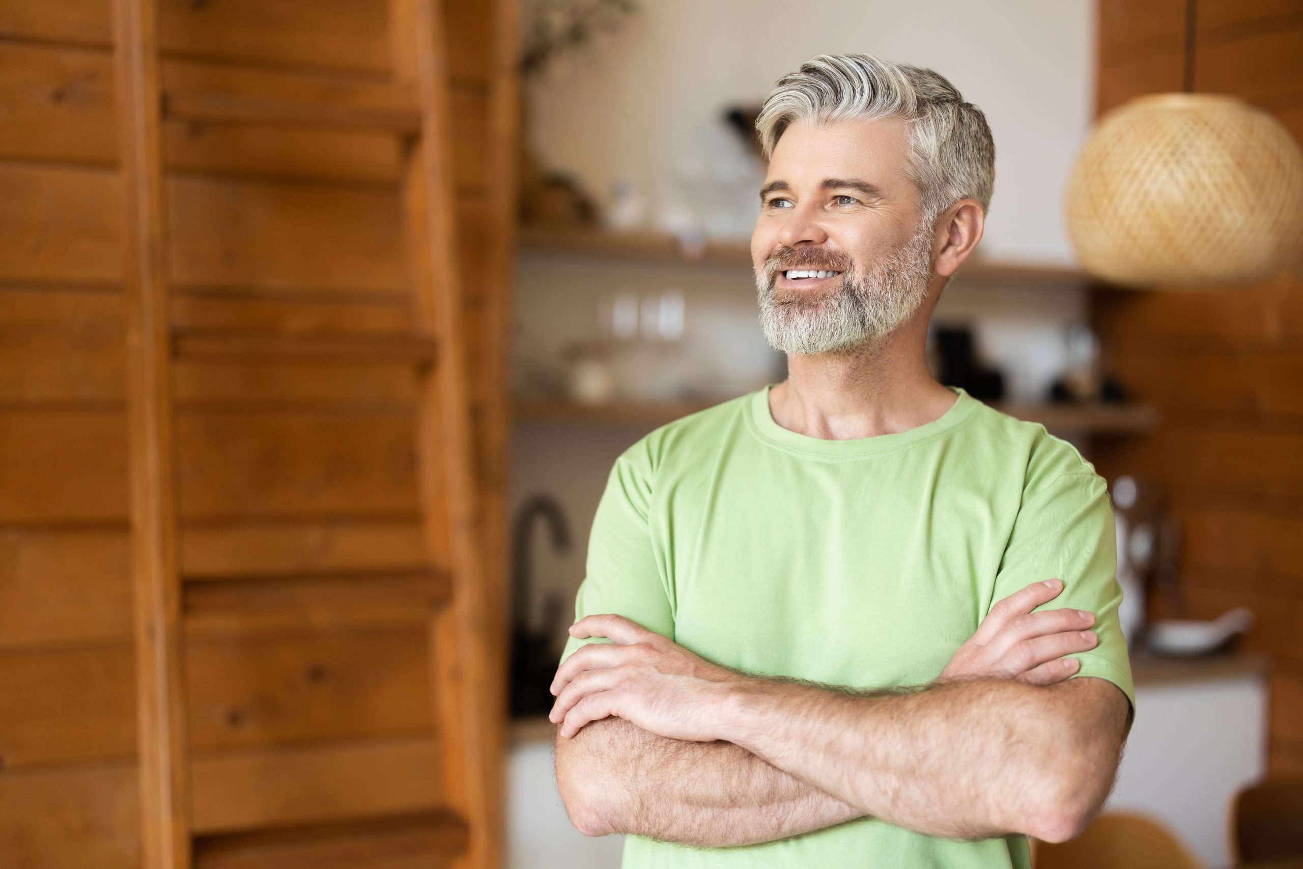 Middle-aged man with arms crossed smiling in modern home interior