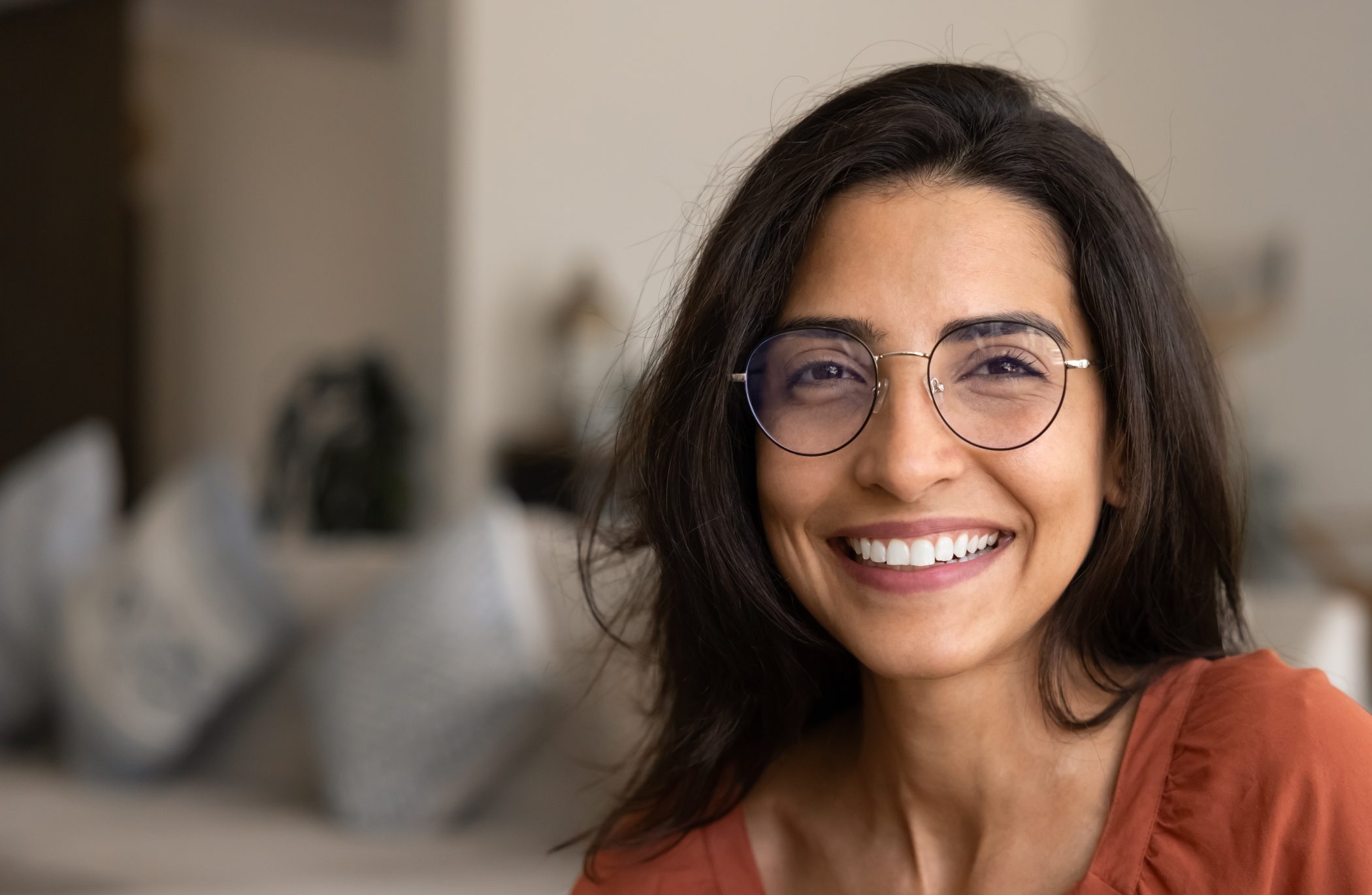 Woman wearing glasses smiling at camera in clinical setting