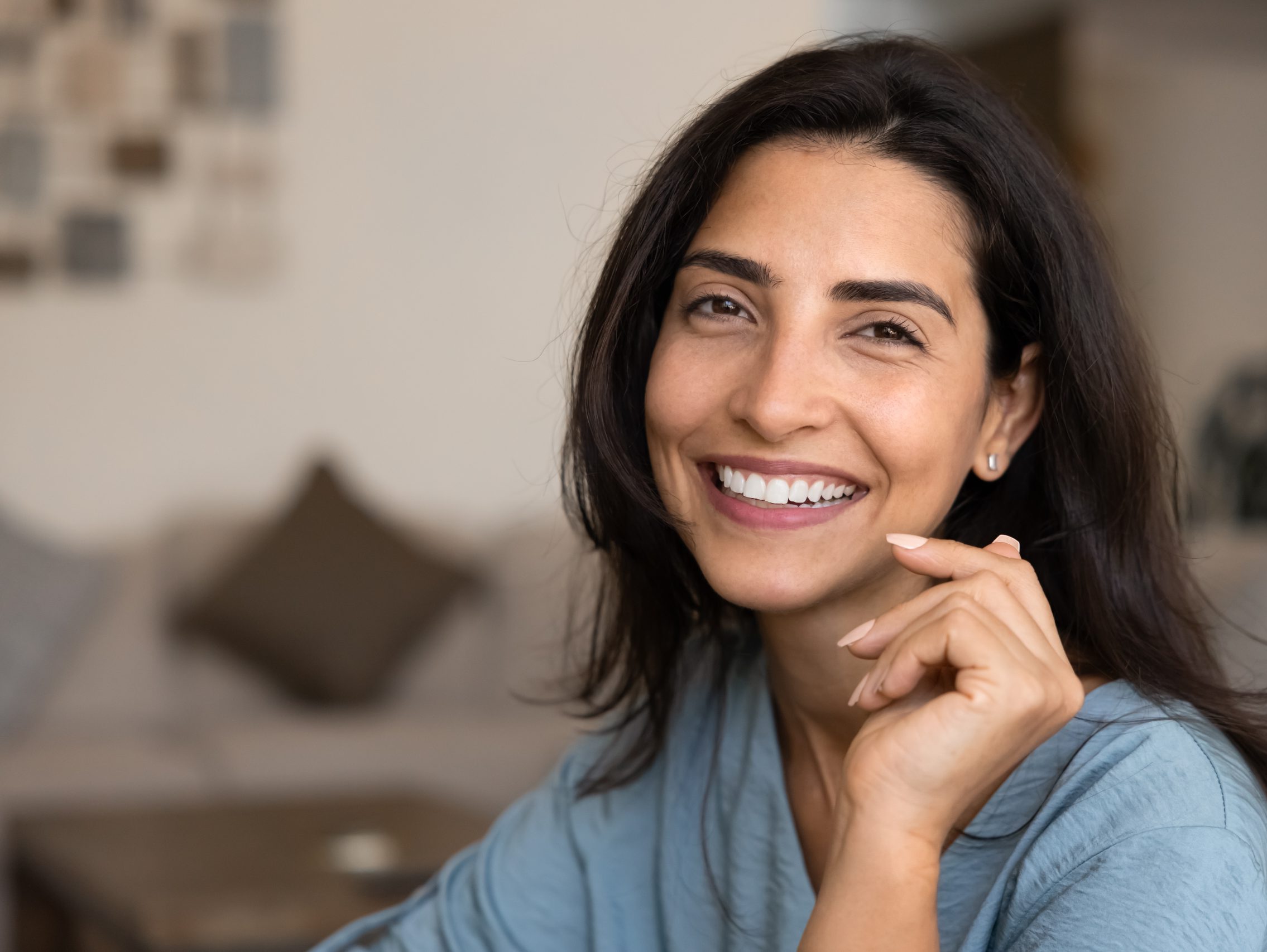 Woman with long dark hair smiling at camera in bright indoor setting