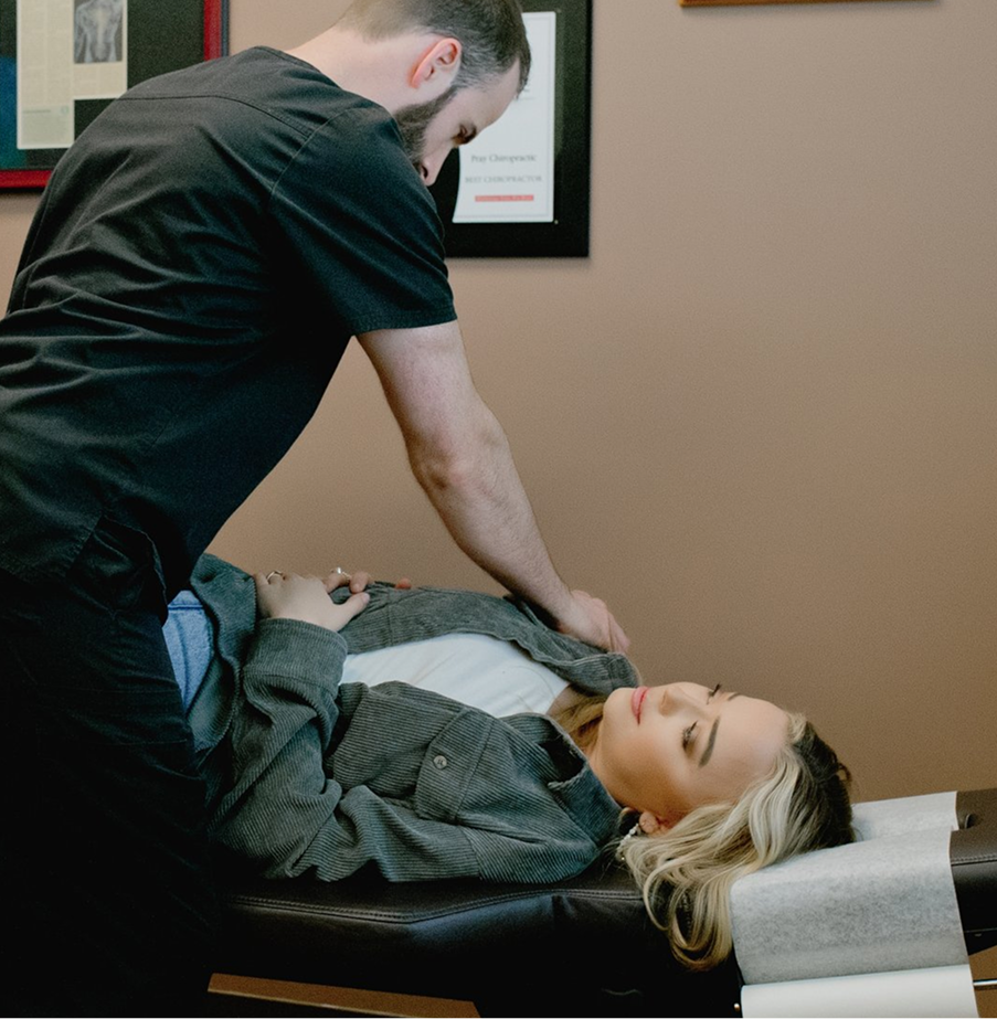 Chiropractor performing spinal manipulation on patient lying on adjustment table
