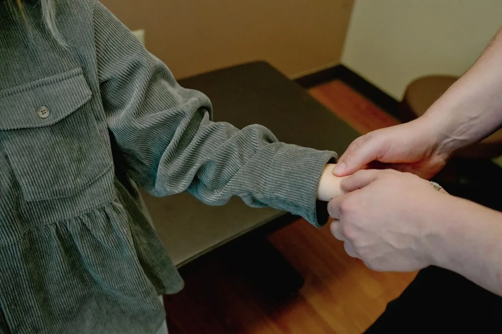 Chiropractor palpating patient's arm during physical examination