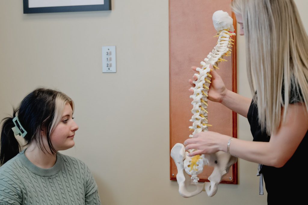 Chiropractor showing patient a spine model during consultation