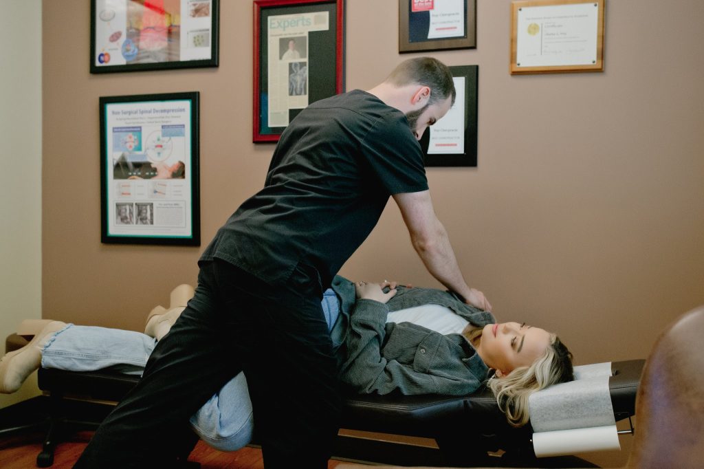 Chiropractor performing spinal manipulation on patient lying on treatment table