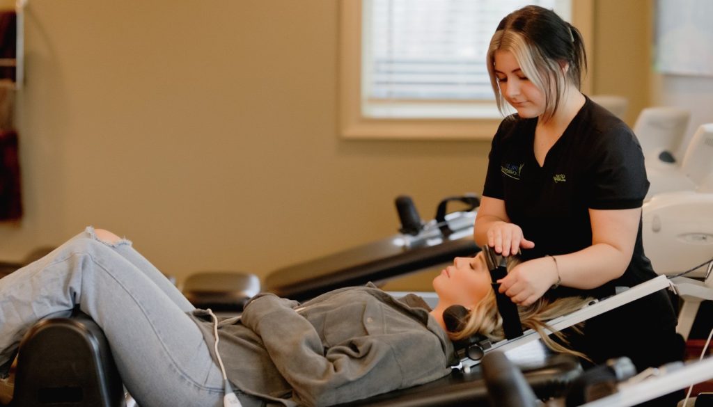 Chiropractor performing ultrasound therapy on patient's shoulder during clinical treatment