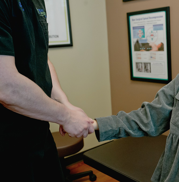 Chiropractor and patient shaking hands in treatment room